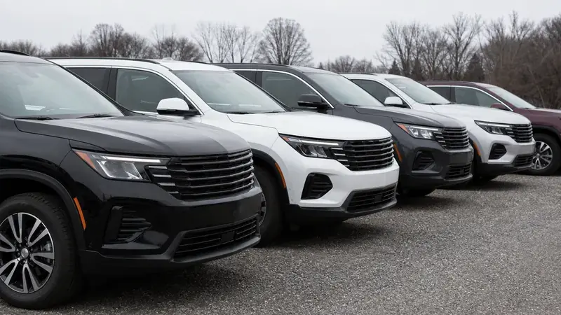 Several SUVs parked in a row on a gravel lot