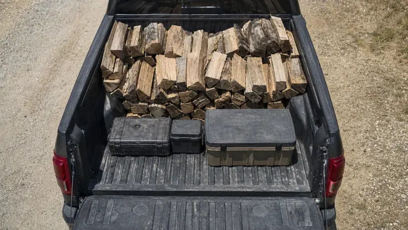 A pickup bed loaded with firewood and storage cases
