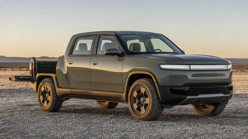 An electric pickup parked on gravel at sunset